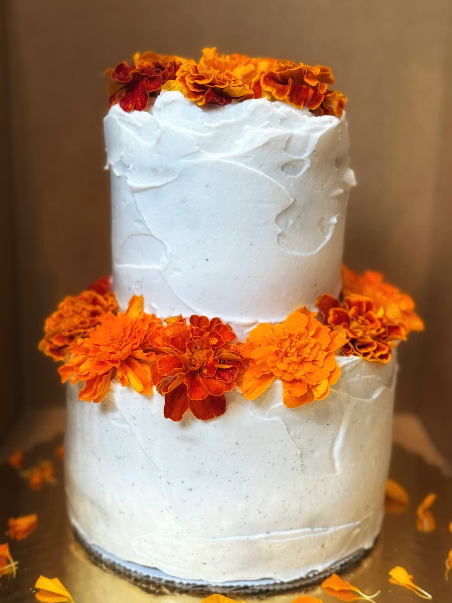 Two-tier vegan cake ringed with fresh marigolds
